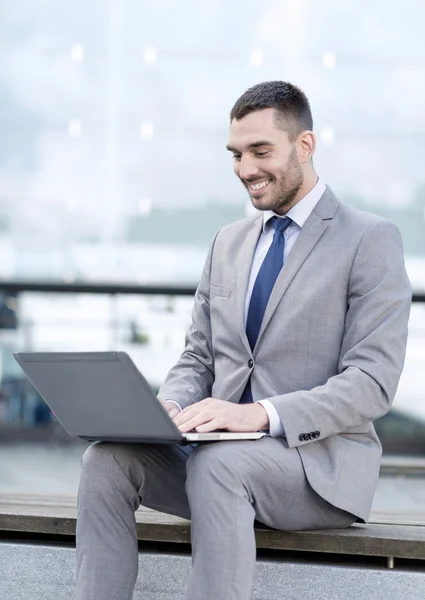 Homme d'affaires souriant travaillant avec ordinateur portable à l'extérieur — Photo