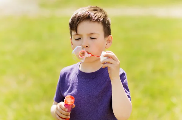 Lille pojken blåser såpbubblor utomhus — Stockfoto