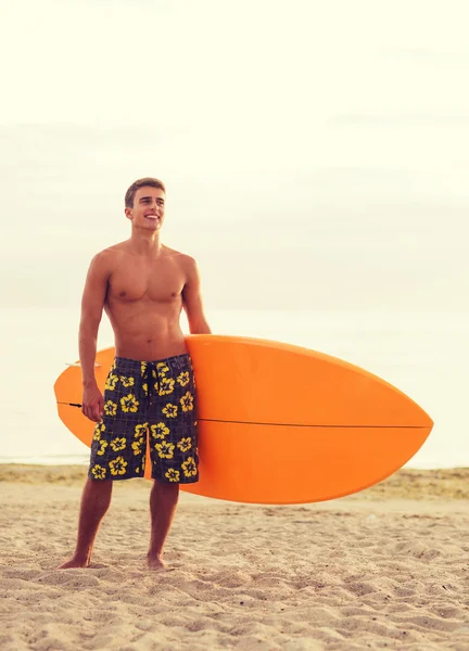 Jeune homme souriant avec planche de surf sur la plage — Photo