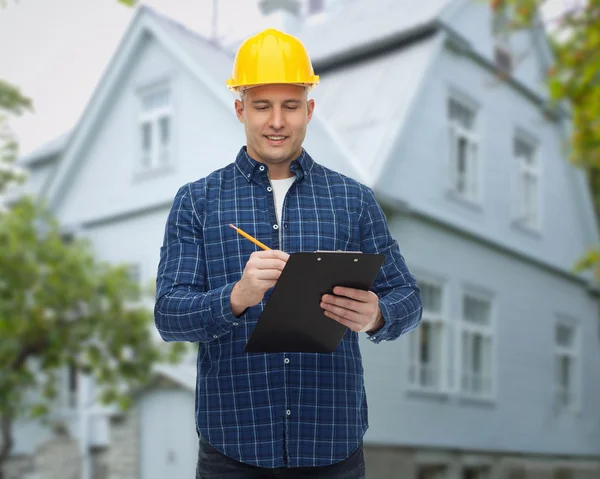 Costruttore maschio sorridente in casco con appunti — Foto Stock