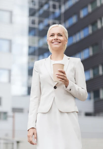 Femme d'affaires souriante avec tasse en papier à l'extérieur — Photo