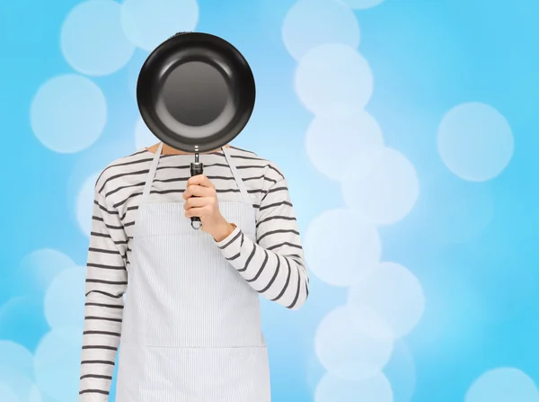 Человек или повар в фартуке скрывая лицо за сковородкой — стоковое фото