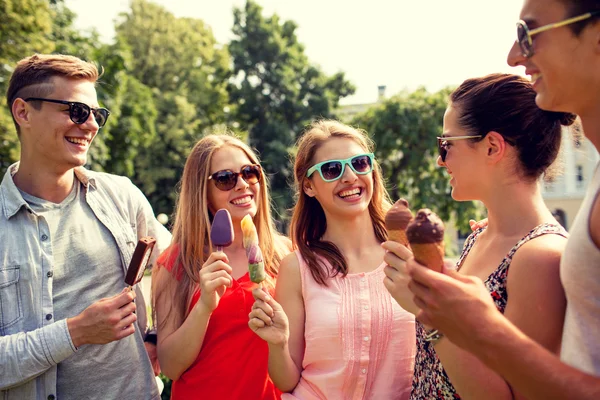 Группа улыбающихся друзей с мороженым на открытом воздухе — стоковое фото