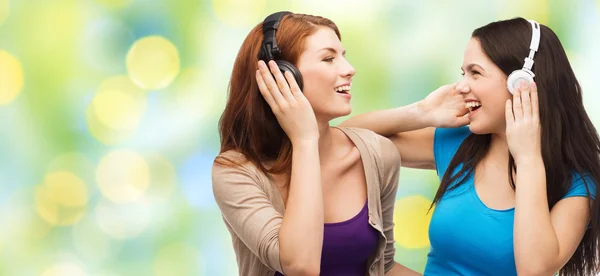 Duas meninas felizes com fones de ouvido ouvindo música — Fotografia de Stock