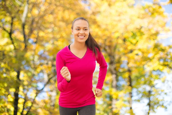 Smiling woman running outdoors at autumn — Stok fotoğraf