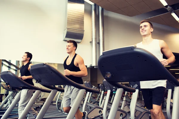 Bărbați zâmbind exercitarea pe banda de alergare în sala de gimnastică — Fotografie, imagine de stoc