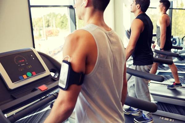 Hombres sonrientes haciendo ejercicio en la cinta de correr en el gimnasio — Foto de Stock