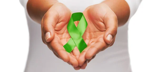 Hands holding green awareness ribbon — Stock Photo, Image