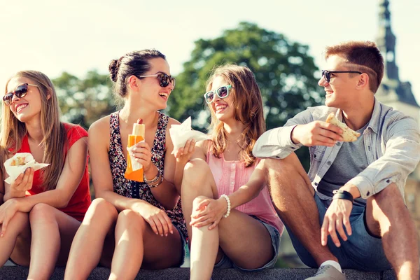 Gruppe lächelnder Freunde sitzt auf dem Stadtplatz — Stockfoto