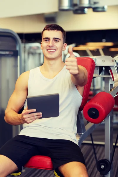 Glimlachend jongeman met tablet pc-computer in de sportschool — Stockfoto