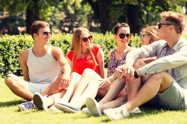 Leende sällskap sitta utomhus på gräs — Stockfoto