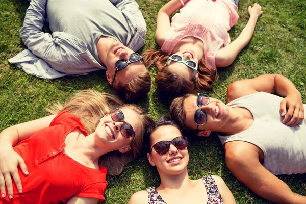 群面带笑容的朋友躺在室外的草地上 — 图库照片