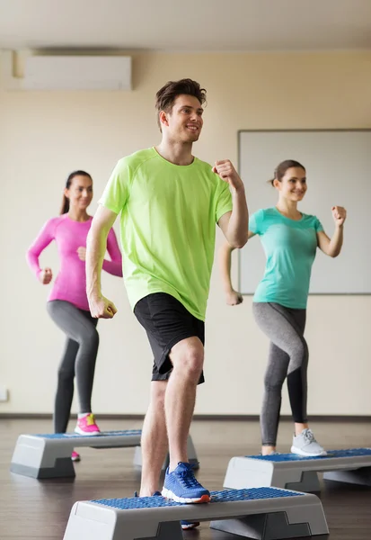 Grupo de personas haciendo ejercicio con los pasos en el gimnasio — Foto de Stock