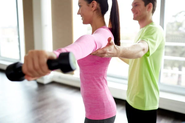 Leende ung kvinna med personlig tränare i gym — Stockfoto