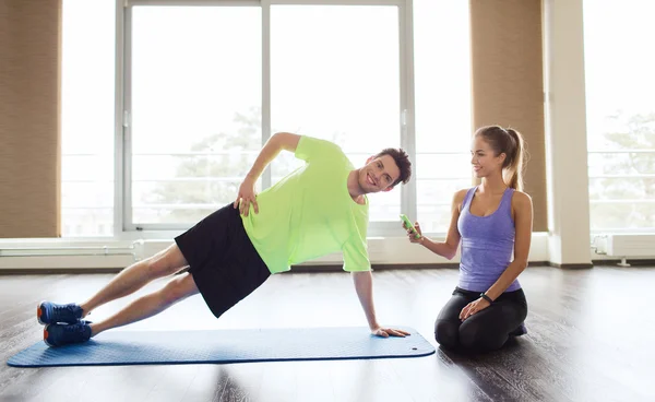 Мужчина и женщина делают упражнения на доске на коврике в спортзале — стоковое фото