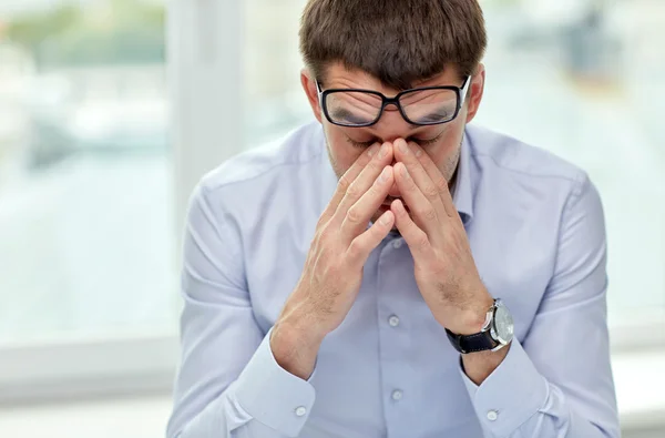 tired businessman with eyeglasses in office