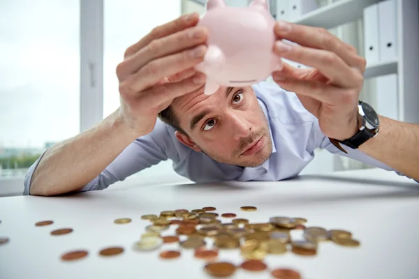 Hombre de negocios con alcancía y monedas en la oficina —  Fotos de Stock