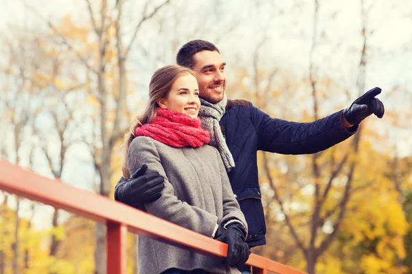 Lächelndes Paar umarmt sich auf Brücke im Herbstpark — Stockfoto