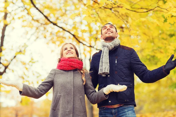 Smiling couple looking up in autumn park — Stock Photo, Image