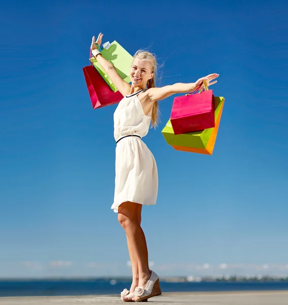 Mulher sorrindo com as mãos subindo saco de compras — Fotografia de Stock