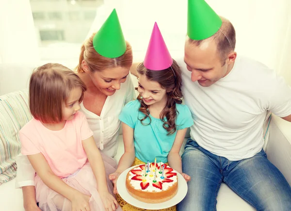 Lächelnde Familie mit zwei Kindern in Hüten mit Kuchen — Stockfoto