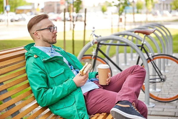 Gelukkig jonge hipster man met koffie en broodje — Stockfoto