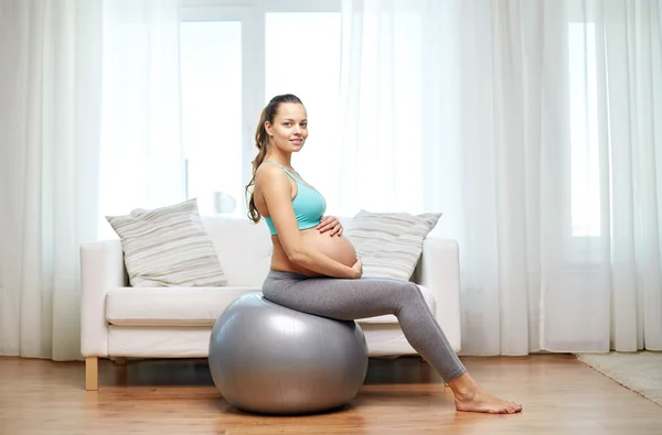 happy pregnant woman exercising on fitball at home
