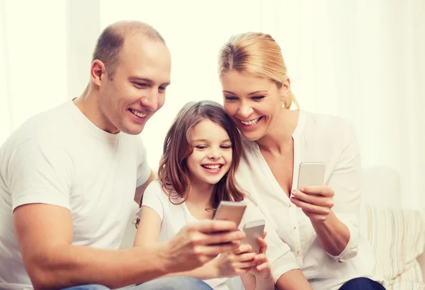 Föräldrar och liten flicka med smartphones hemma — Stockfoto