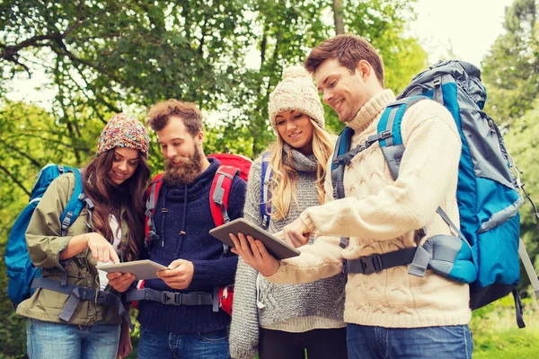 Groep vrienden met rugzakken en tablet pc — Stockfoto