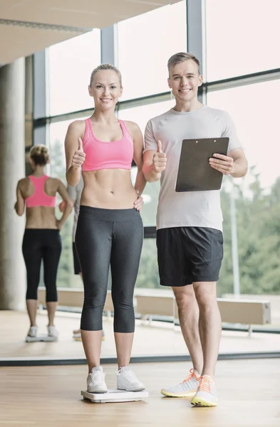 Uomo e donna sorridente con bilance in palestra — Foto Stock