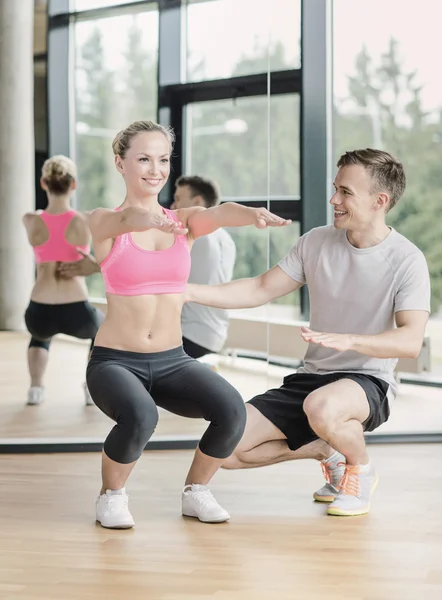 Wanita tersenyum dengan pelatih laki-laki berolahraga di gym — Stok Foto