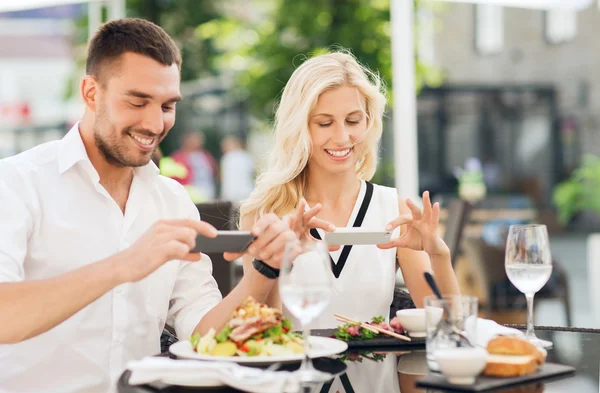 Feliz pareja con smatphone fotografiando comida —  Fotos de Stock