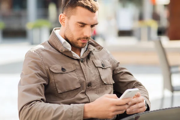 Man with smartphone at city street cafe — Stock Photo, Image