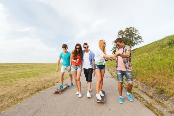 Счастливые друзья-подростки с длинными досками на улице — стоковое фото