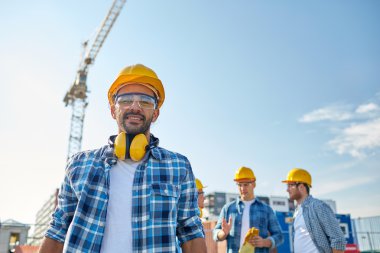 group of smiling builders in hardhats outdoors clipart