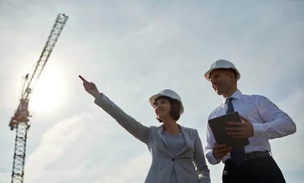 Constructores felices en sombreros con tableta pc al aire libre — Foto de Stock