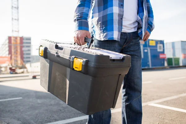 Close up of builder carrying toolbox outdoors — Stock Photo, Image