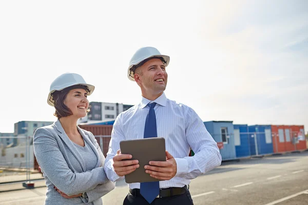Construtores felizes em hardhats com tablet pc ao ar livre — Fotografia de Stock