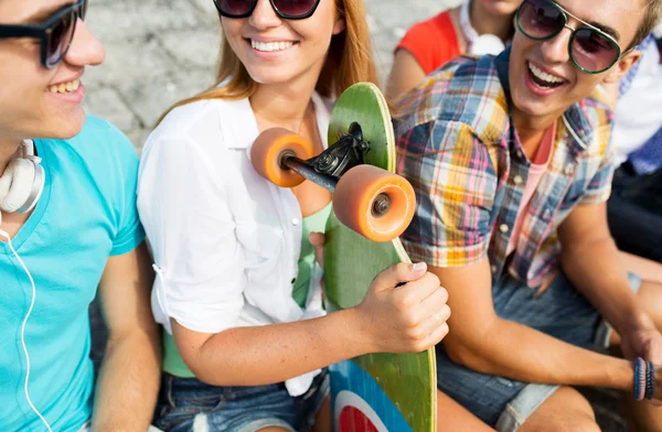 Close up of happy friends with longboard on street — Stockfoto