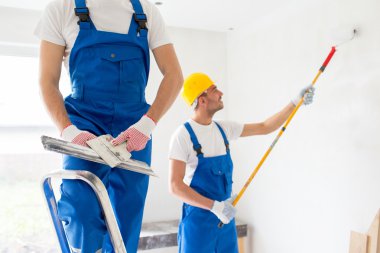two builders with painting tools repairing room clipart
