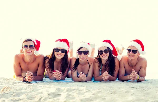 Group of friends in santa helper hats on beach — Stock Photo, Image