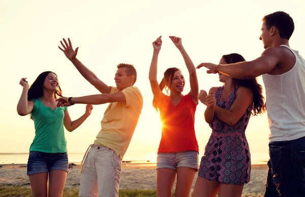 Lachende vrienden dansen op zomer strand — Stockfoto