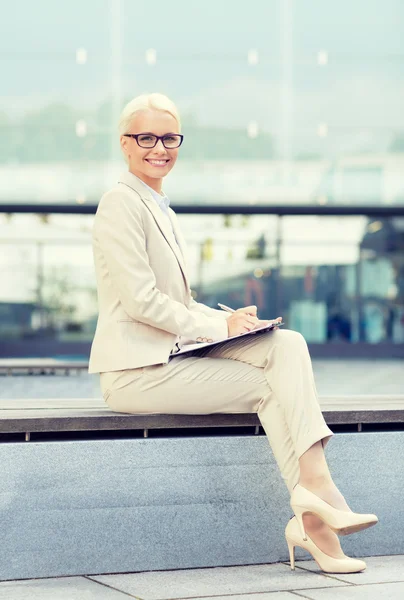 Jeune femme d'affaires souriante avec bloc-notes à l'extérieur — Photo