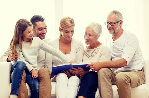 Família feliz com livro ou álbum de fotos em casa — Fotografia de Stock