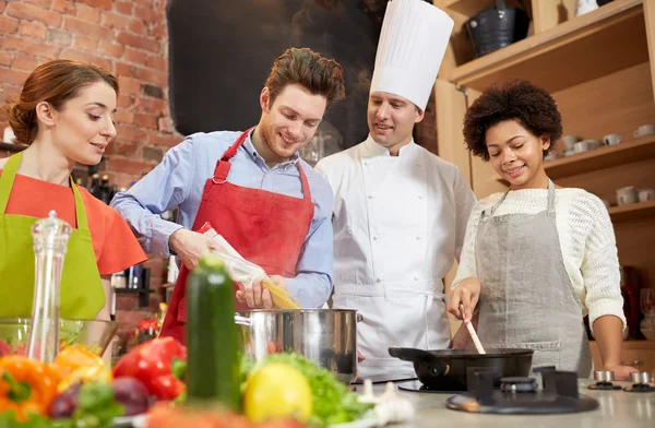 Amis heureux et chef cuisinier cuisine dans la cuisine — Photo