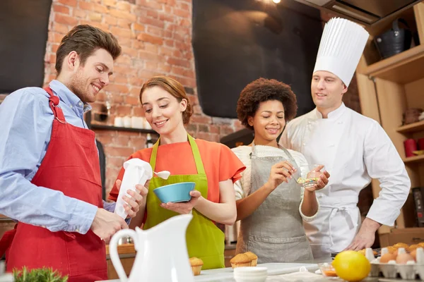 Amigos felizes e cozinheiro chef assar na cozinha — Fotografia de Stock