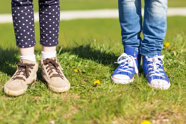 Close up of kids legs in shoes on grass outdoors — Zdjęcie stockowe