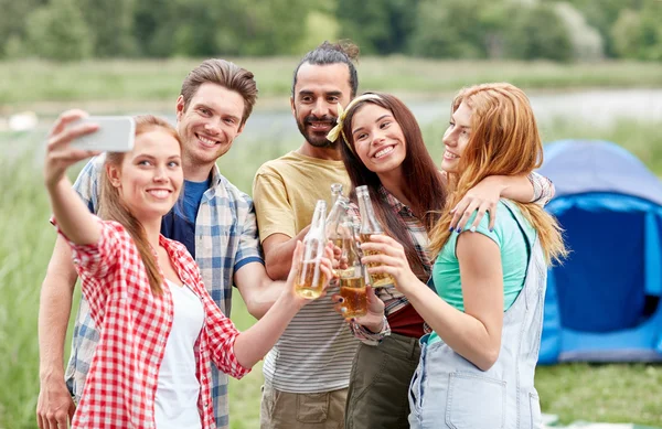 Amigos felizes tirando selfie por smartphone no acampamento — Fotografia de Stock