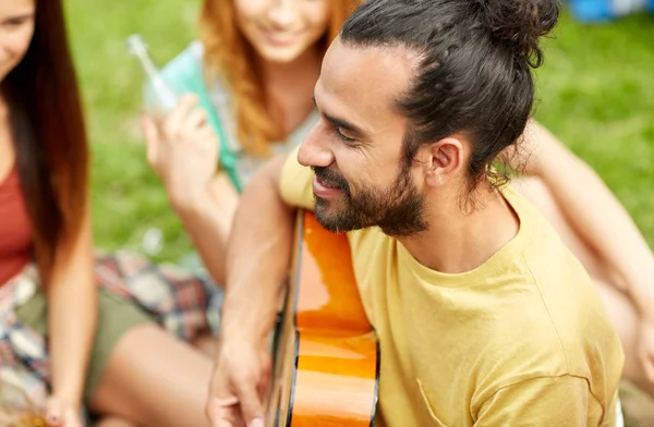 Lycklig man med vänner spelar gitarr på camping — Stockfoto