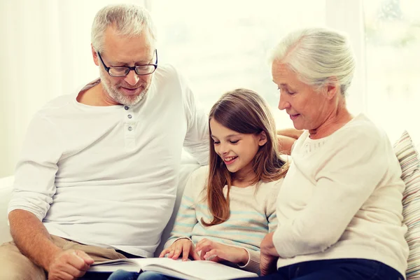 Famille souriante avec livre à la maison Images De Stock Libres De Droits